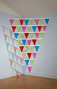 a large triangular, flat sculpture made of smaller triangular pennant flags of transparent multi colored vinyl.