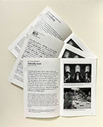 A set of three zines, in English, German, and Japanese, opened to the introductory essay with a photo of the library.