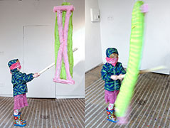 a young girl in a raincoat swings at the ironing board piñata, two images showing the motion