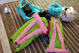 A pile of broken piñatas on a concrete floor