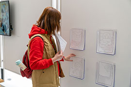 A woman takes coloring sheets from wall holders.