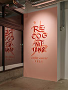 A pink wall with the exhibition title in Chinese in peach paint, with the English text in red on top.
