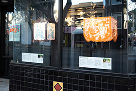 Photo of a storefront of black tile with two lanterns in the windows.