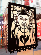 A lantern of purple metal with a portrait of a woman split in sad and happy halves.