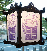 A wooden lantern with a purple papercut showing a cross section of an SRO apartment building.