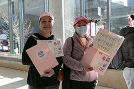 Two smiling women holding up colorful folders